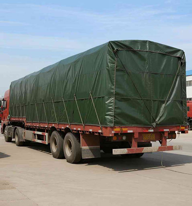 Truck covered with green PVC tarpaulin for cargo protection