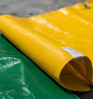 Rolled yellow and green PVC tarpaulin fabric