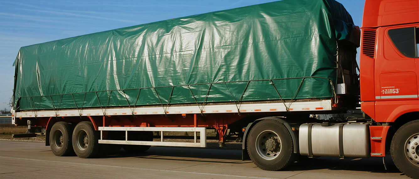 Truck with cargo covered by green PVC tarpaulin