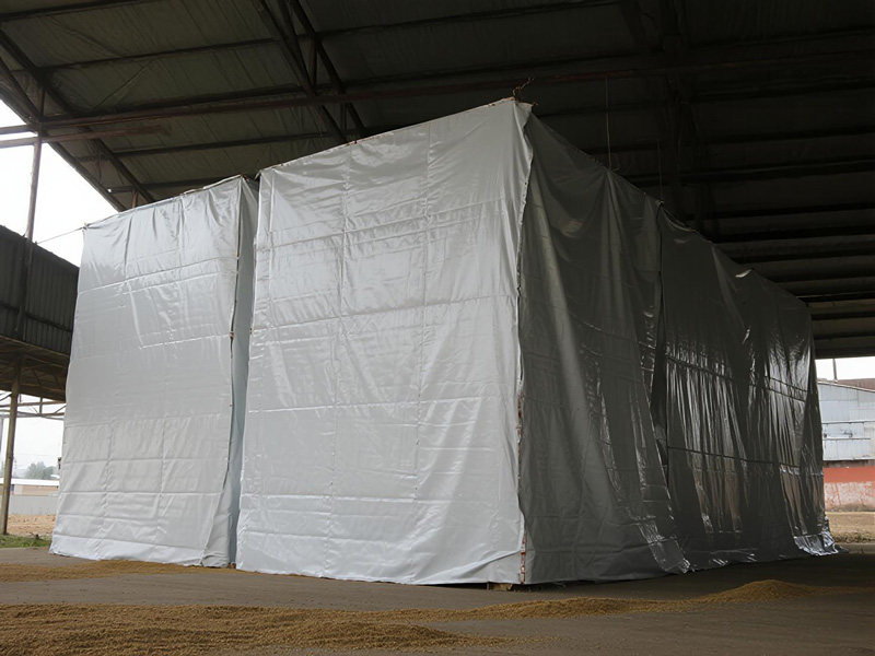 Workers securing grain cover around storage silo