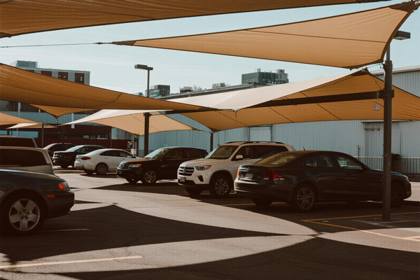 Commercial parking lot with shade cloth canopy covering multiple vehicles