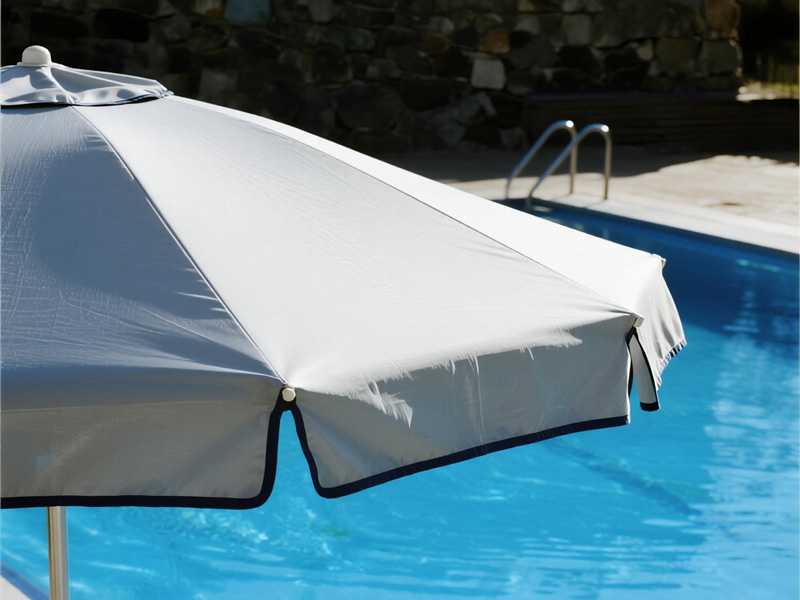Swimming pool area with rain cover protecting deck and lounge chairs during rainfall
