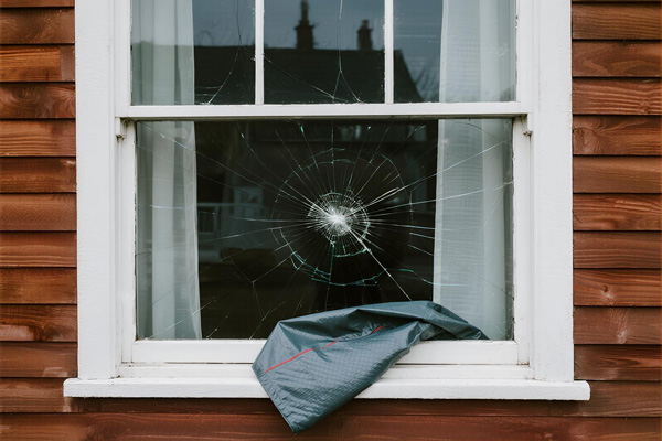 Storm damaged window covered with emergency protection sheet