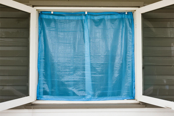 Vacation home with window damage protected by emergency cover