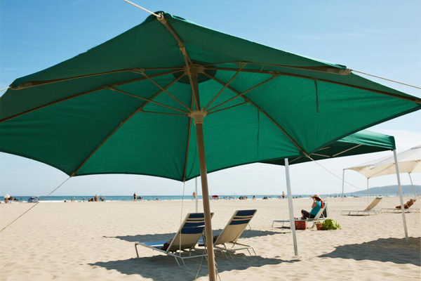 Sun shade tarp at beach with people relaxing underneath