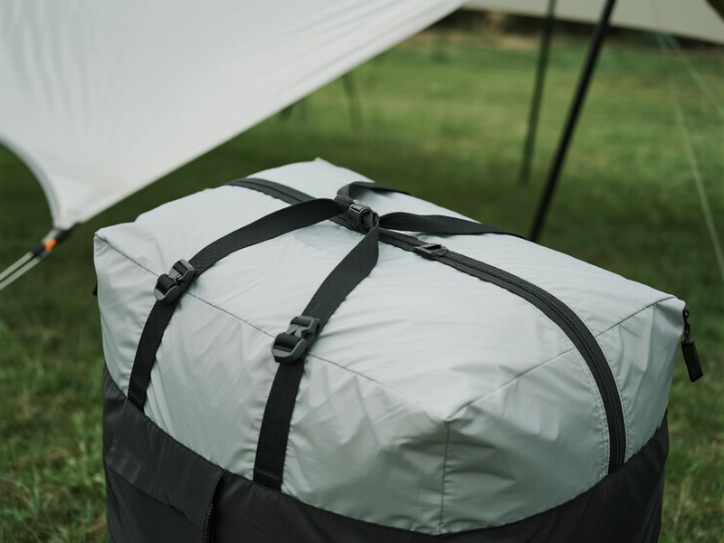 Camping gear stored under waterproof storage tarp in rainy conditions