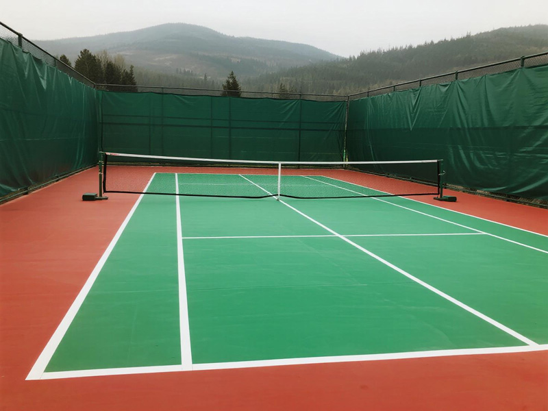 Outdoor badminton court with temporary cover providing shade and protection