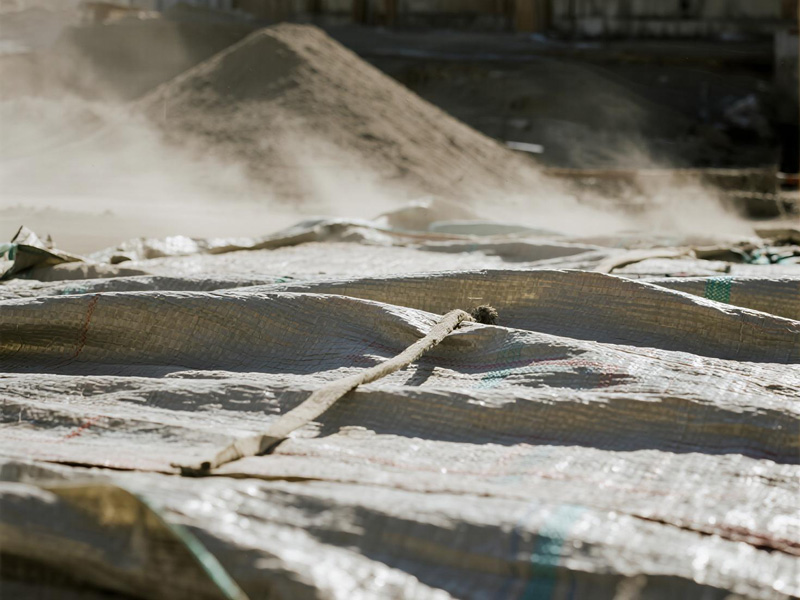 Construction site with cement and gravel piles covered by heavy-duty rain tarp