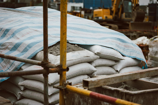 Cement bags protected by rain tarp on construction site