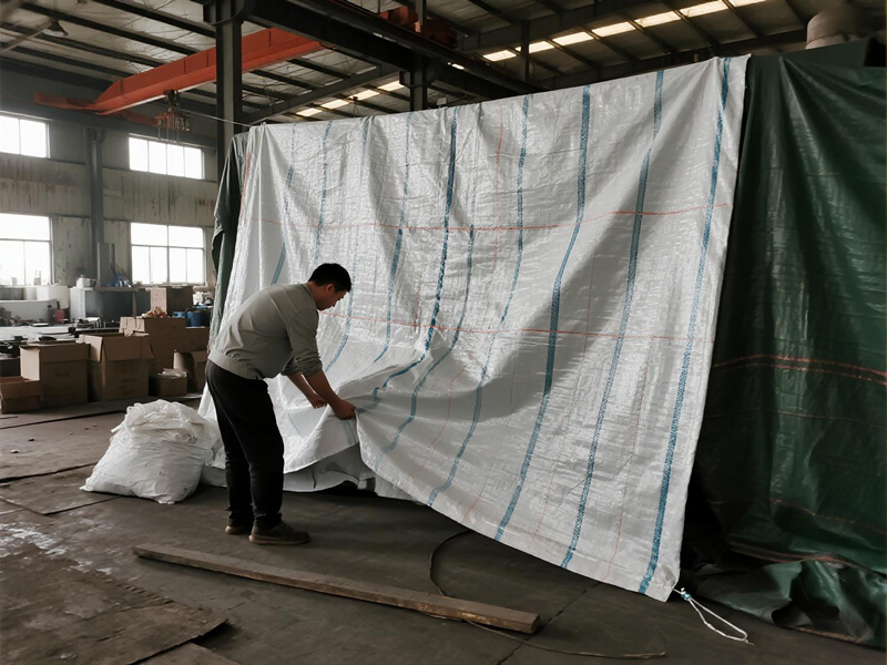 Warehouse interior with emergency tarp covering leak area and protecting stored goods