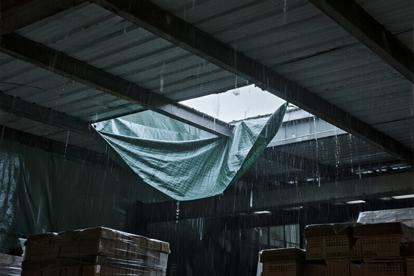 Emergency tarp covering roof leak in large warehouse