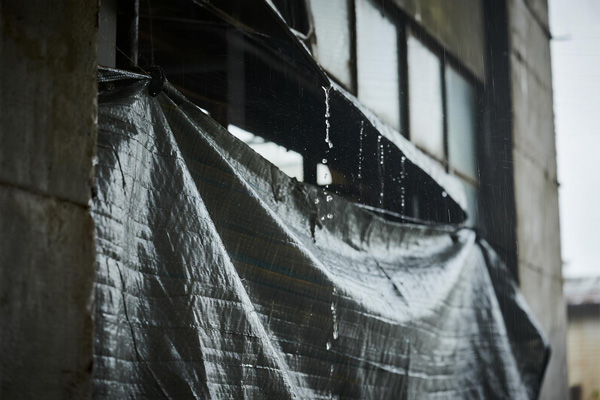 Emergency tarp creating barrier against warehouse wall leaks