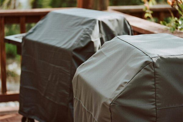 Covered charcoal grill in backyard setting