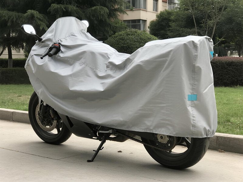 Motorcycle covered with waterproof dust cover in outdoor setting