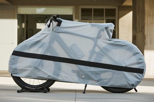 Bicycle covered with dust cover in urban apartment balcony